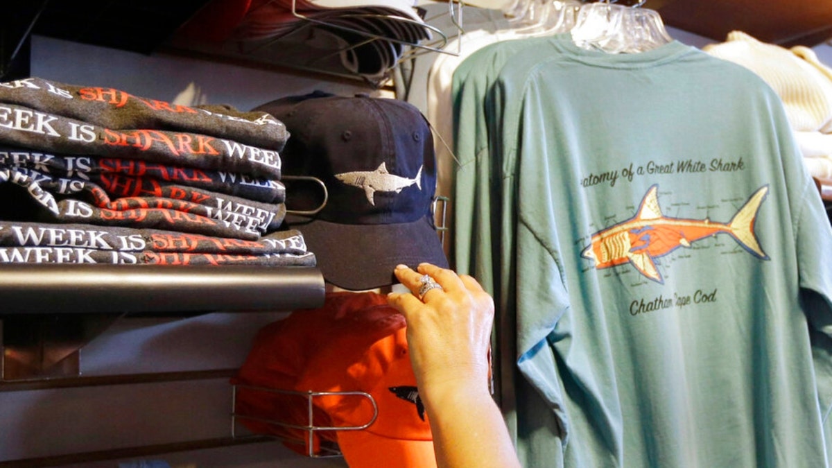 In this July 2, 2014 photo, a customer examines shark-themed clothing at a store in Chatham, Massachusetts. 