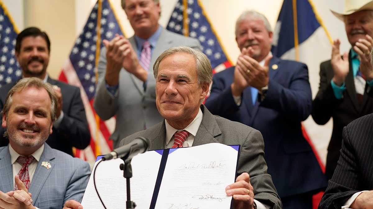 Texas Gov Greg Abbott shows off Senate Bill 1, also known as the election integrity bill, after he signed it into law in Tyler, Texas, Tuesday, Sept. 7, 2021. The sweeping bill signed Tuesday by the two-term Republican governor further tightens Texas’ strict voting laws. (AP Photo/LM Otero)