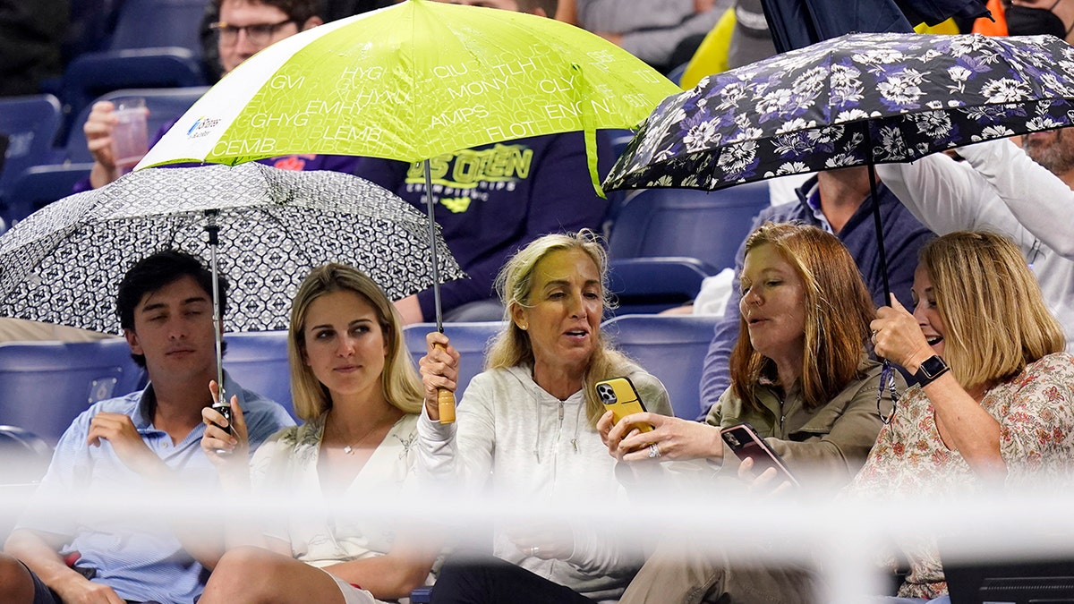 Fans cover themselves from rain in Louis Armstrong Stadium during a match between Kevin Anderson, of South Africa, and Diego Schwartzman, of Argentina, in the second round of the US Open tennis championships, Wednesday, Sept. 1, 2021, in New York. (AP Photo/Frank Franklin II)