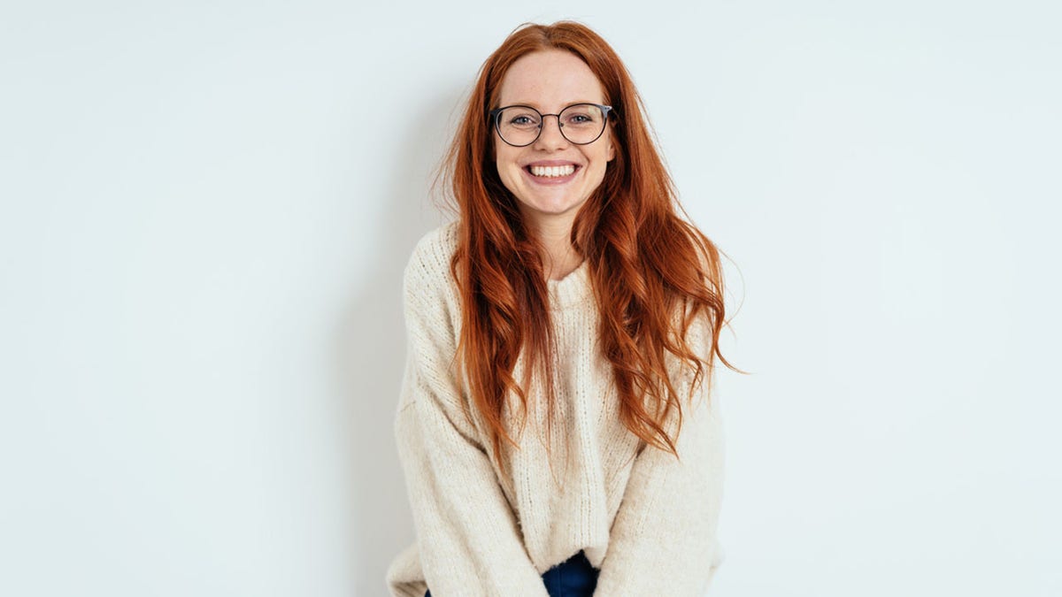 Model smiling at camera wearing a white sweater