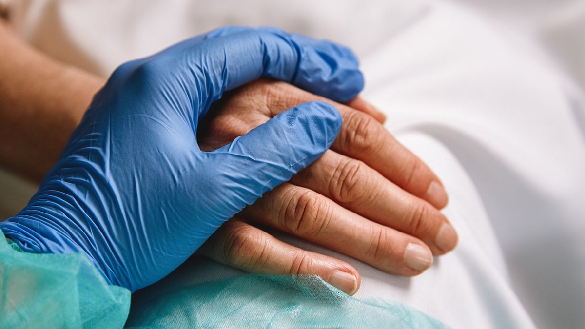 Health care worker holding patients hand