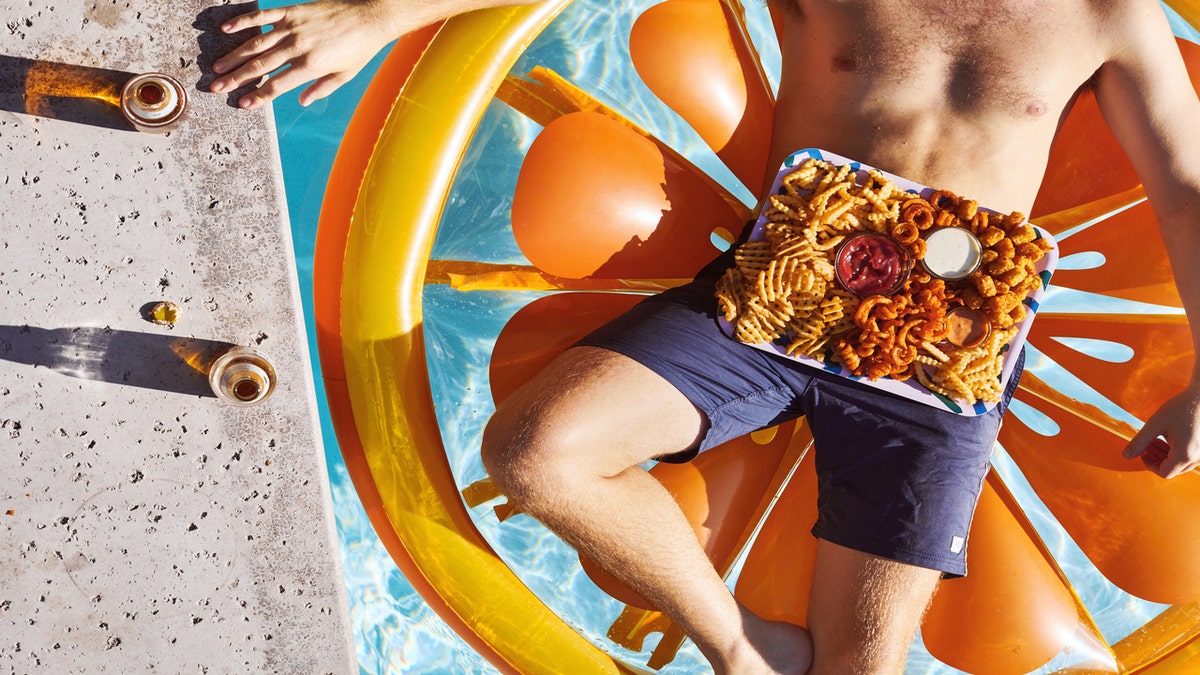 Man floats in pool with French fry platter