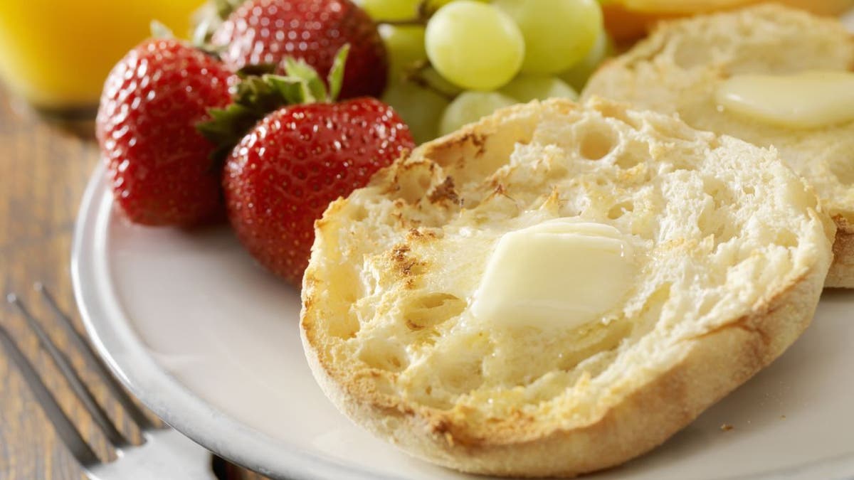 English Muffins with Melted Butter on plate with strawberries and grapes in background