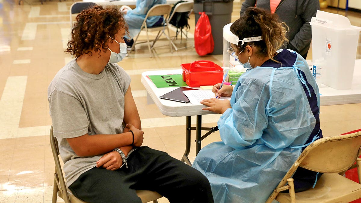 A student waits to receive the COVID-19 vaccine at the Woodrow Wilson Senior High School in Los Angeles, California.