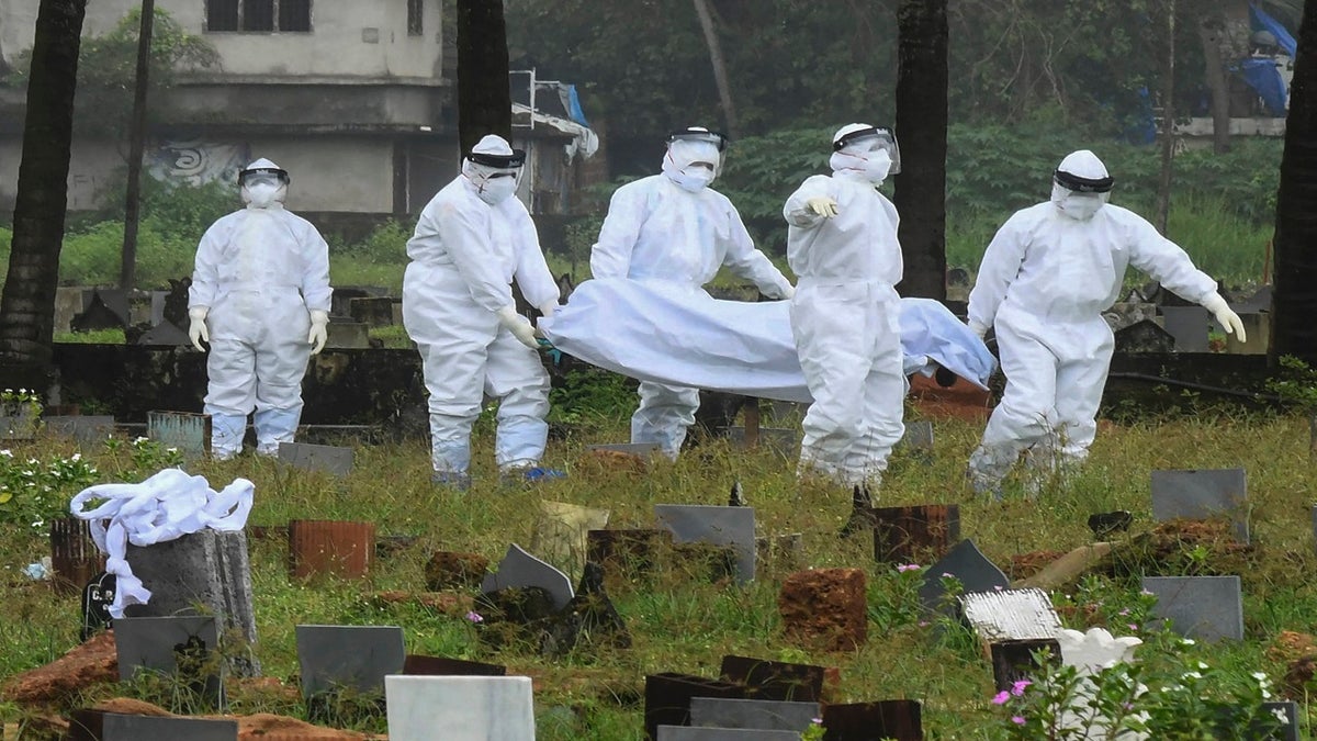 Sept. 5, 2021: People in protective suits prepare to cremate the body of a 12-year-old boy who died of the Nipah virus in Kozhikode, Kerala state, India. 