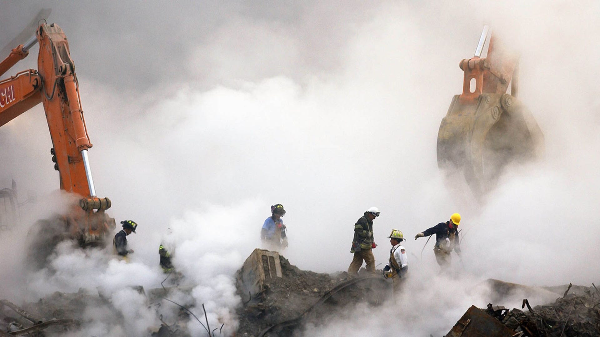 Firefighters make their way over the ruins through clouds of smoke as work continues at ground zero in New York, one month after the attacks on the World Trade Center, Oct. 11, 2001. (REUTERS/Stan Honda/POOL ME/HK)