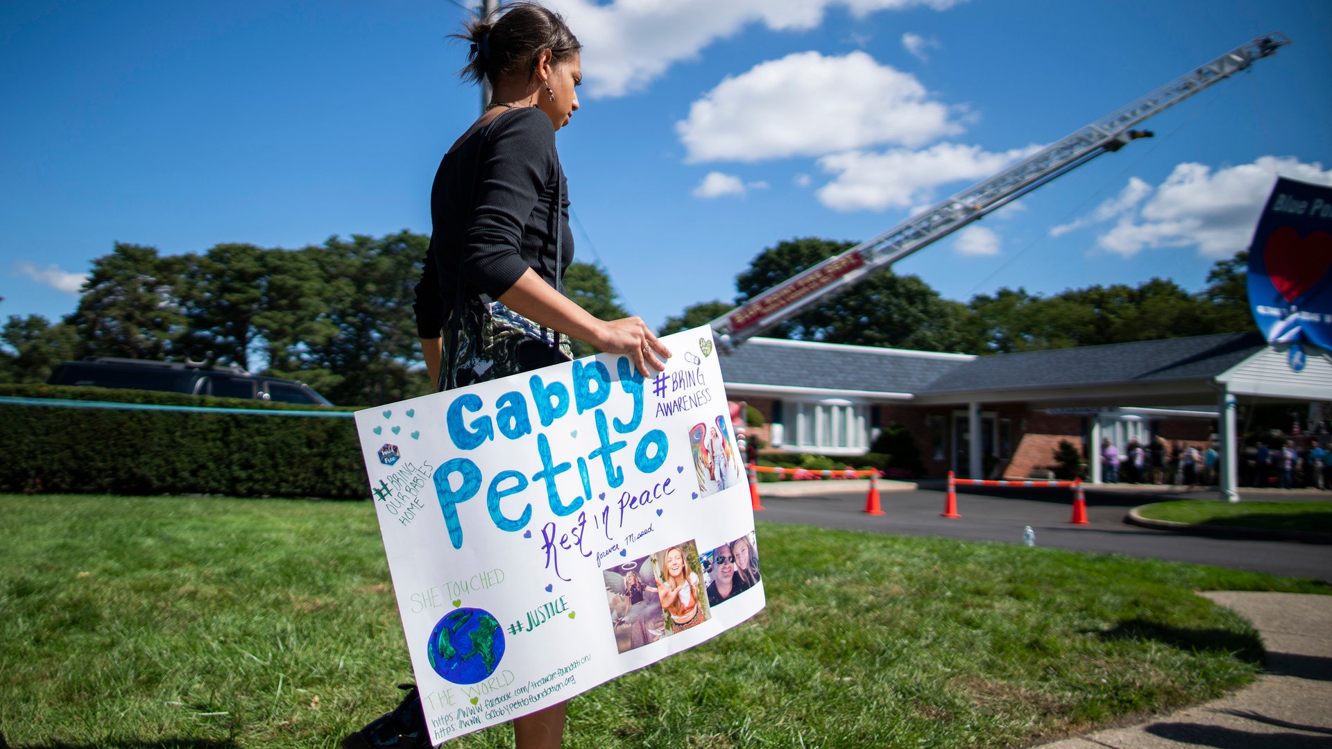  A woman carries a placard in honor of Petito as people attend the funeral home viewing of Gabby Petito at Moloney's Funeral Home in Holbrook, N.Y. Sunday, Sept. 26, 2021. 