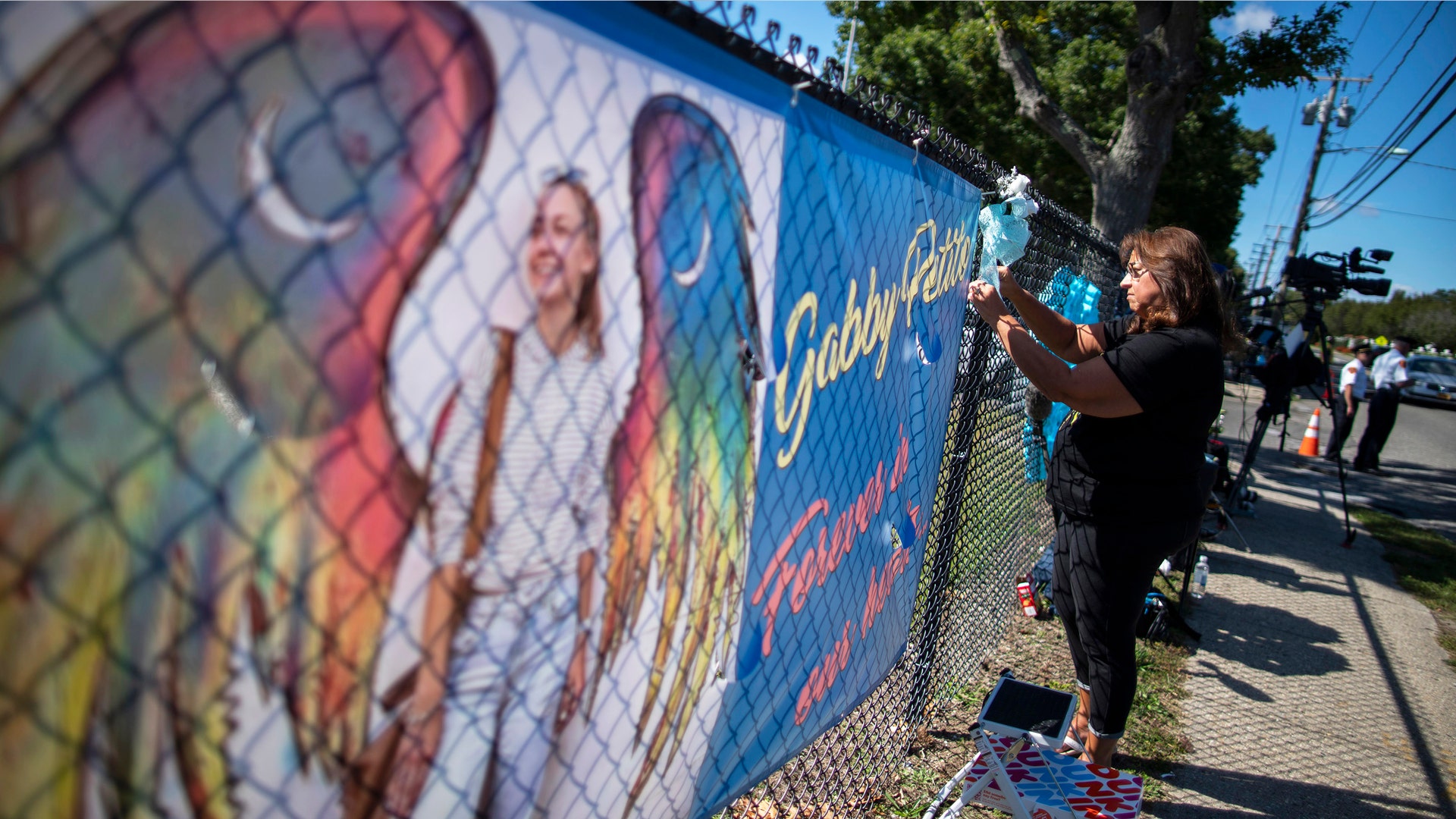  A woman places a decoration near a poster after attending the funeral home viewing of Gabby Petito at Moloney's Funeral Home in Holbrook, N.Y. Sunday, Sept. 26, 2021. 