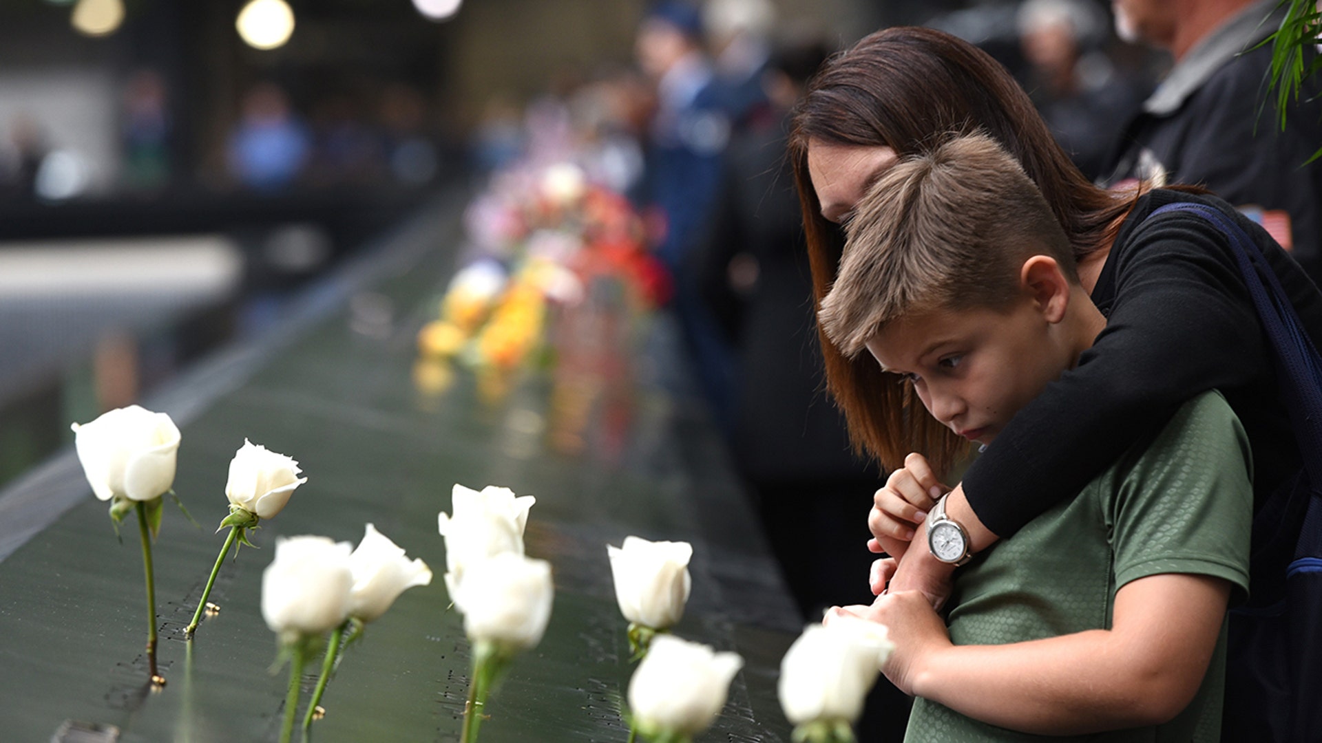 A young boy and his mother looks down into the South Pool during observances on Sept. 11, 2018, held on the 17th year since the September 11, 2001, terror attacks at the annual ceremony at the Ground Zero memorial site. (TIMOTHY A. CLARY/AFP via Getty Images)