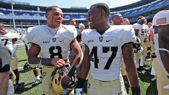 Army football players run out on field carrying American flags
