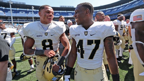 Army football players run out on field carrying American flags