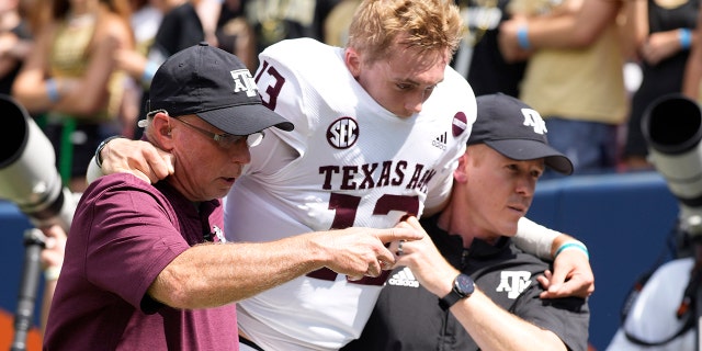 Texas A&M quarterback Haynes King, centro, is helped off the field after being injured in the first half of an NCAA college football game against Colorado, Sabato, Sett. 11, 2021, a Denver.