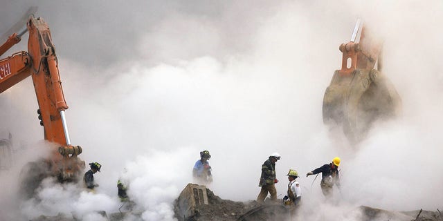 Firefighters make their way over the ruins through clouds of smoke as work continues at ground zero in New York, one month after the attacks on the World Trade Center, October 11, 2001. 