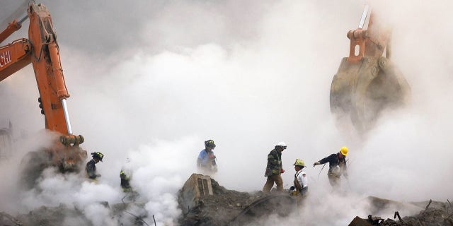 Firefighters make their way over the ruins through clouds of smoke as work continued at Ground Zero in New York, one month after the attacks on the World Trade Center, Oct. 11, 2001. Weisberg still suffers from respiratory issues, GERD and PTSD as a result of helping out in Lower Manhattan.