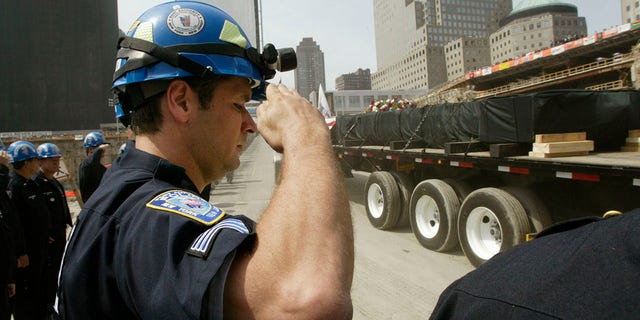 FILE – The final beam to be cut down at the World Trade Center is driven away on a truck shrouded in black as New York and New Jersey Port Authority Police salute during a ceremony to mark the end of the recovery effort on the site in New York, May 30, 2002. The beam was the ceremonial last load to be taken from the site. The World Trade Centers collapsed when attacked by hijacked airplanes September 11, 2001. REUTERS/Mike Segar MS