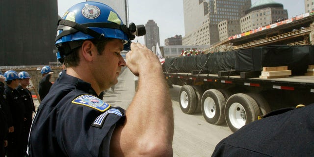 FILE – The final beam to be cut down at the World Trade Center is driven away on a truck shrouded in black as New York and New Jersey Port Authority Police salute during a ceremony to mark the end of the recovery effort on the site in New York, 할 수있다 30, 2002. The beam was the ceremonial last load to be taken from the site. The World Trade Centers collapsed when attacked by hijacked airplanes September 11, 2001. REUTERS/Mike Segar MS