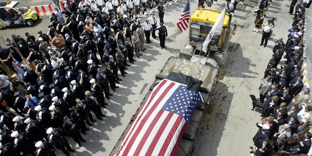 The last steel girder left standing at the World Trade Center, covered with black cloth and an American flag, is carried from the World Trade Center site in New York on May 30, 2002, marking the completion of recovery work from the September 11, 2001, attacks on the twin towers.  New York marked the end of the mammoth recovery of human remains and disposal of the ruins of the World Trade Center with a brief ceremony, nearly nine months after two hijacked planes slammed into the twin towers, destroying them and killing 2,823 people.