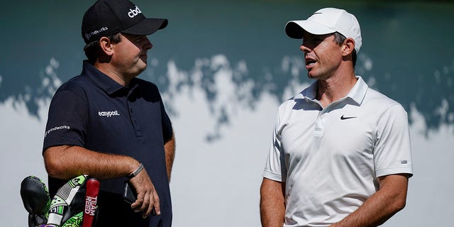 Patrick Reed, left, and Rory McIlroy, right, talk on the first tee during practice at the Tour Championship golf tournament Sept. 1, 2021, at East Lake Golf Club in Atlanta.