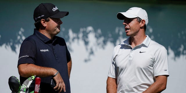 Patrick Reed, left, and Rory McIlroy, right, talk on the first tee during practice at the Tour Championship golf tournament on September 1, 2021, at East Lake Golf Club in Atlanta.