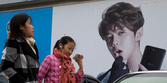In this 2017, file photo, Chinese women walk past advertisement featuring teen idol Lu Han, also known as China's Justin Bieber in Beijing.