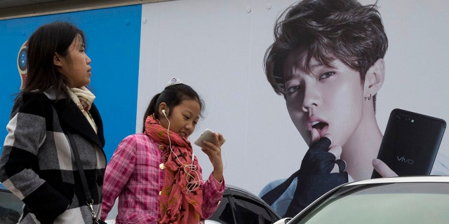 In this 2017, file photo, Chinese women walk past advertisement featuring teen idol Lu Han, also known as China's Justin Bieber in Beijing.