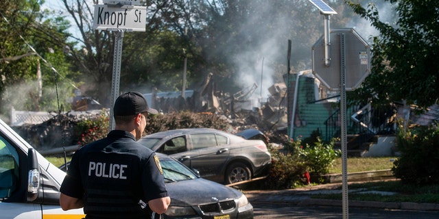 A Manville Police Officer stands guard near the remains of a house that exploded due to severe flooding from Tropical Storm Ida in Manville, NJ., Friday. Dozens of people in five states died as storm water cascaded into people’s homes and engulfed automobiles, overwhelming urban drainage systems never meant to handle so much rain in such a short time.