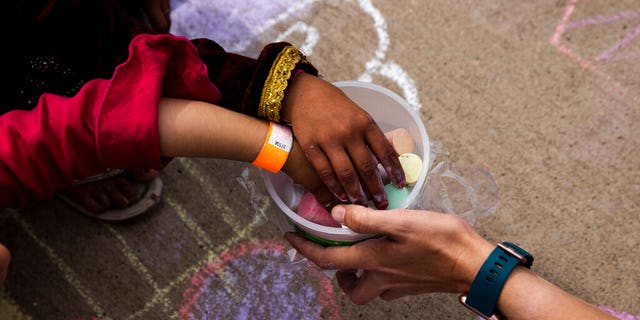 In this Aug. 31 , 2021, photo provided by the U.S. Army, Afghan children take a piece of chalk at a children's activity event held by non-governmental charities at Fort McCoy in Wisconsin. (Spc. Rhianna Ballenger/U.S. Army via AP)