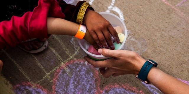 In this Aug. 31 , 2021, photo provided by the U.S. Army, Afghan children take a piece of chalk at a children's activity event held by non-governmental charities at Fort McCoy in Wisconsin. (Spc. Rhianna Ballenger/U.S. Army via AP)