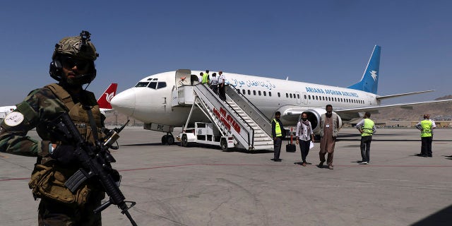 A Taliban soldier stands guard as passengers disembark on arrival from Kandahar, at Hamid Karzai International Airport in Kabul, Afghanistan, Sunday, Sept. 5, 2021. (AP Photo/Wali Sabawoon)
