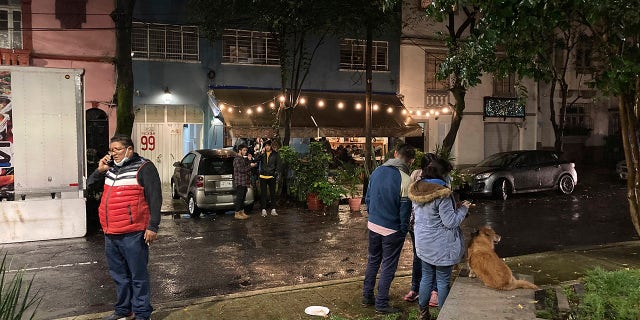 People gather outside on the sidewalk after a strong earthquake was felt, in the Roma neighborhood of Mexico City, Tuesday, Sept. 7, 2021. (AP Photo/Leslie Mazoch)