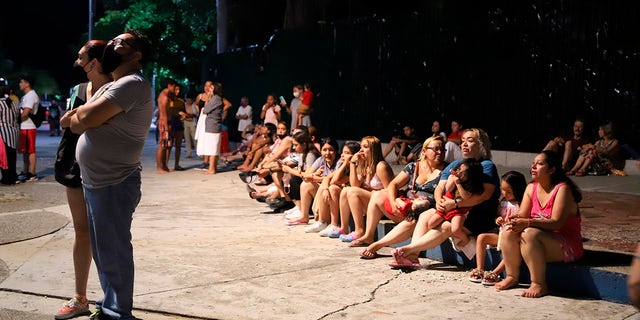 Locals sit on a sidewalk after a strong earthquake in Acapulco, Mexico, Tuesday, Sept. 7, 2021. The quake struck southern Mexico near the resort of Acapulco, causing buildings to rock and sway in Mexico City nearly 200 miles away. (AP Photo/ Bernardino Hernandez)