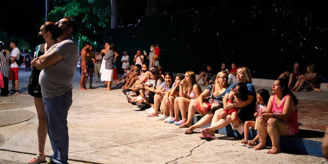 Locals sit on a sidewalk after a strong earthquake in Acapulco, Mexico, Tuesday, Sept. 7, 2021. The quake struck southern Mexico near the resort of Acapulco, causing buildings to rock and sway in Mexico City nearly 200 miles away. (AP Photo/ Bernardino Hernandez)