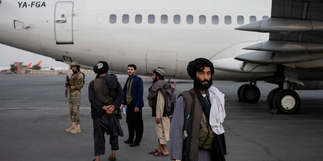 Taliban personnel stand beside a plane at the airport in Kabul, Afghanistan, Thursday, Sept. 9, 2021. (AP Photo/Bernat Armangue)