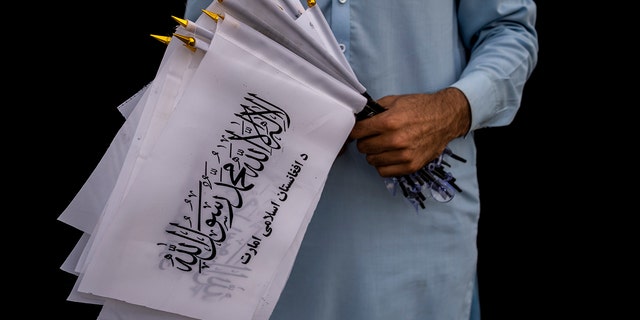 A street vendor selling Taliban flags waits for customers outside the U.S. Embassy compound in Kabul, Afghanistan on Saturday, September 11, 2021.