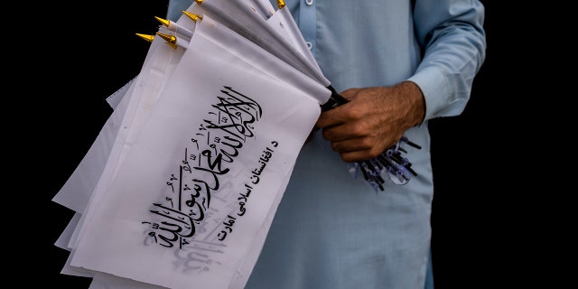 A street vendor selling Taliban flags waits for customers outside the American embassy compound in Kabul, Afghanistan, Saturday, Sept. 11, 2021.