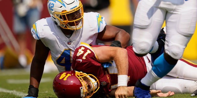 Washington Football Team quarterback Ryan Fitzpatrick (14) reacting after getting tackled by Los Angeles Chargers linebacker Uchenna Nwosu (42) during a game Sept. 12, 2021, in Landover, Md. 