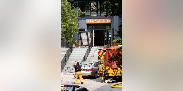 A firefighter carries a ladder past the damaged leasing center following an apartment building explosion, Sunday, Sept. 12, 2021, in Dunwoody, Ga., just outside of Atlanta.
