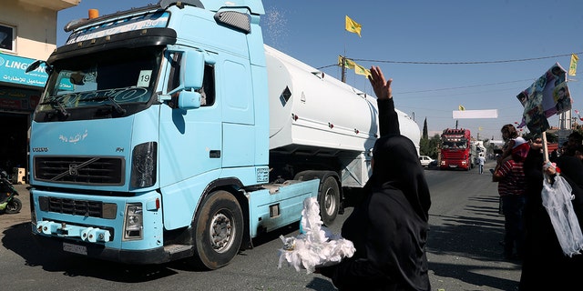 A Hezbollah supporter pours rice over a convoy of Iranian diesel tankers crossing the border from Syria into Lebanon, arriving at the eastern city of El-Ain, Lebanon, on Thursday, September 16, 2021. 