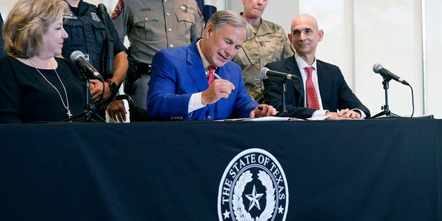 Texas Gov Greg Abbott, front center, is flanked by officials as he signs a bill that provides additional funding for security at the U.S.-Mexico border on Sept. 17. (AP Photo/LM Otero)