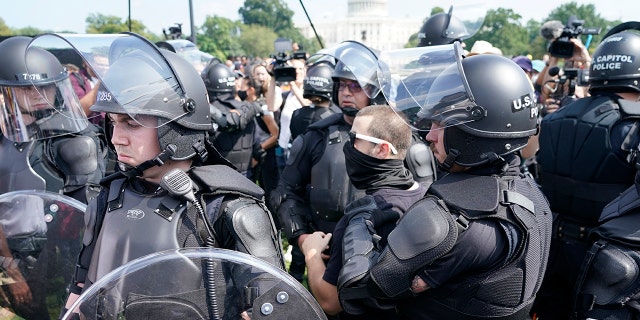 Police circle a man, center with glasses, during a rally near the U.S. Capitol in Washington, Saturday, Sept. 18, 2021. The rally was planned by allies of former President Donald Trump and aimed at supporting the so-called