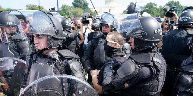 Police circle a man, center with glasses, during a rally near the U.S. Capitol in Washington, Saturday, Sept. 18, 2021. The rally was planned by allies of former President Donald Trump and aimed at supporting the so-called 