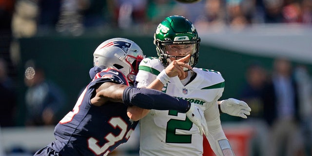 New York Jets quarterback Zach Wilson throws under pressure from New England Patriots' Joejuan Williams Sunday, 九月. 19, 2021, 位于东卢瑟福, 新泽西州. 