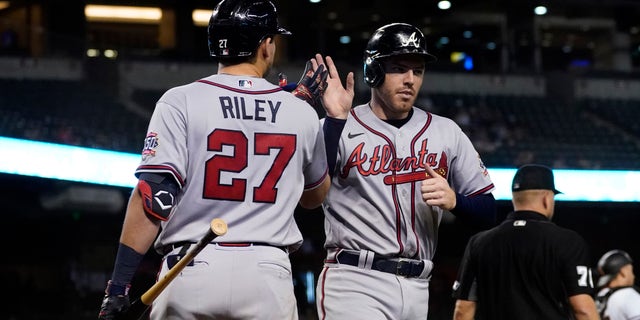Atlanta Braves' Freddie Freeman high fives Austin Riley (27) after scoring on a double hit by Ozzie Albies during the fifth inning of a baseball game against the Arizona Diamondbacks, Monday, Sept. 20, 2021, in Phoenix.