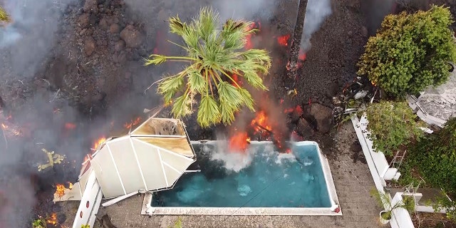 Hot lava reaches a swimming pool after an eruption of a volcano on the island of La Palma in the Canaries, Spain, Monday, Sept. 20, 2021.
