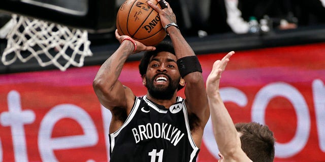 FILE - Brooklyn Nets guard Kyrie Irving (11) shoots against the Milwaukee Bucks during the second half of Game 1 of an NBA basketball second-round playoff series in New York, in this Saturday, June 5, 2021, file photo. Players like Kyrie Irving, who has refused to say if he will be vaccinated against COVID-19, will be subject to testing on all NBA practice, travel and game days this season. Fully vaccinated players will not. (AP Photo/Adam Hunger, File)