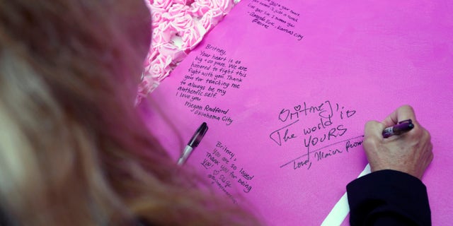 Marion Kaiser, of Tucson, Ariz., writes words of support to singer Britney Spears on a poster outside the Stanley Mosk Courthouse, Wednesday, Sept. 29, 2021, in Los Angeles.