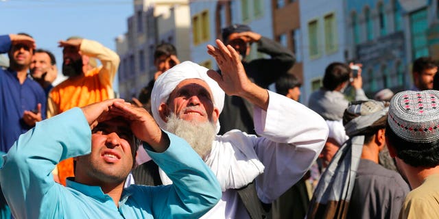 CORRECTS DAY TO SEPT 25 - People look up at a dead body hanged by the Taliban from a crane in the main square of Herat city in western Afghanistan, on Saturday Sept. 25, 2021. A witness told The Associated Press that the bodies of four men were brought to the main square and three of them were moved to other parts of the city for public display. The Taliban announced in the square that the four were caught taking part in a kidnapping and were killed by police. (美联社照片)