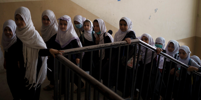 Girls walk upstairs as they enter a school before class in Kabul, Afghanistan, Sunday, Sept. 12, 2021.