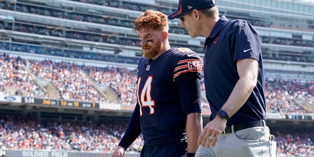 Chicago Bears quarterback Andy Dalton walks to the locker room with an unidentified trainer during the first half of an NFL football game against the Cincinnati Bengals Sunday, Sept. 19, 2021, in Chicago.