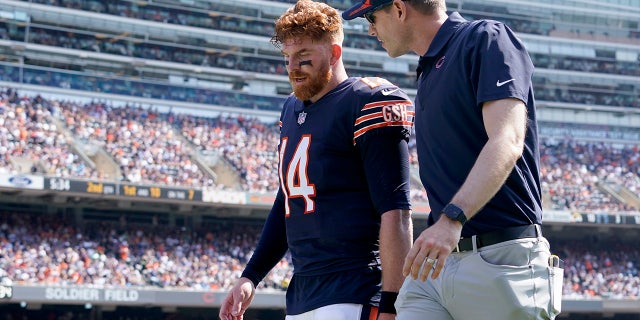 Chicago Bears quarterback Andy Dalton walks to the locker room with an unidentified trainer during the first half of an NFL football game against the Cincinnati Bengals Sunday, Sept. 19, 2021, in Chicago.